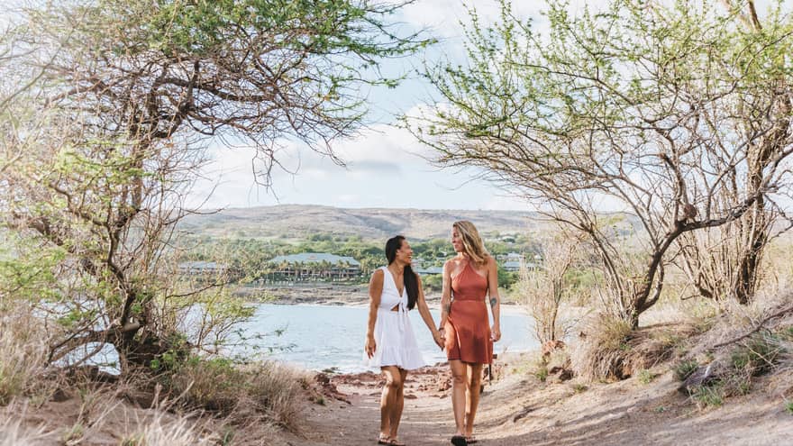 Two women walk hand in hand near Lanai beach