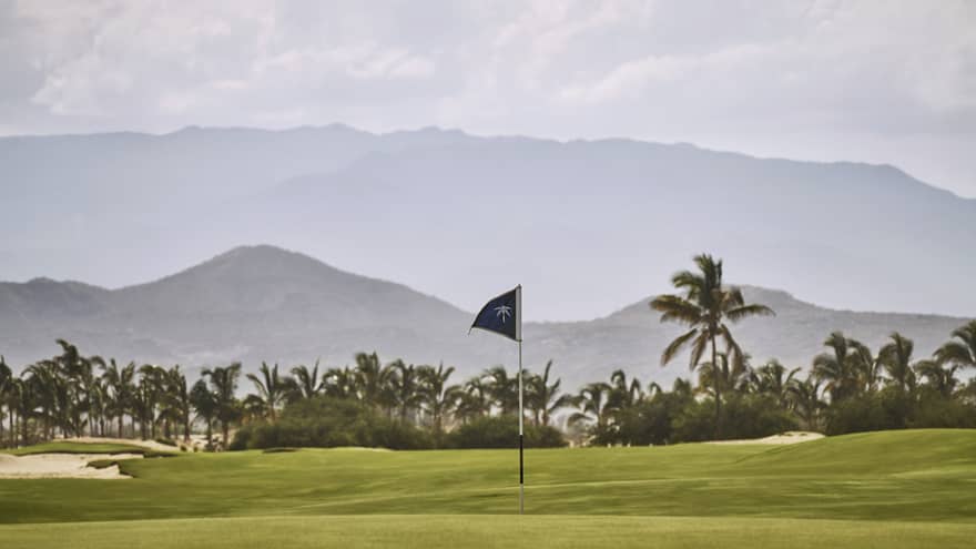 A putting green with a view of tropical trees and mountains behind