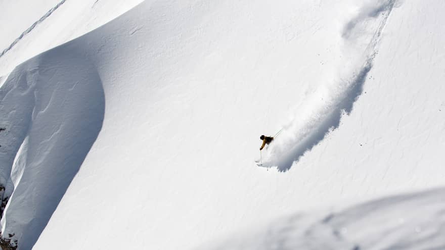 A person skiing down a slope of white snow.