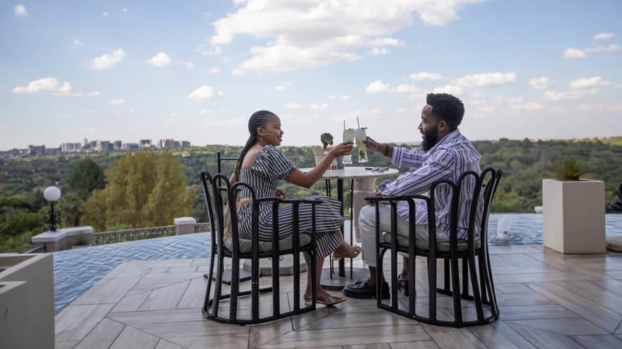 Couple toasting Champagne while seated at terrace bistro table