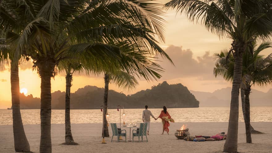 A man and woman on a beach having a Punta chintai private dinner at Four Seasons Langkawi
