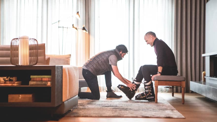 One man helping another to put on ski shoes.
