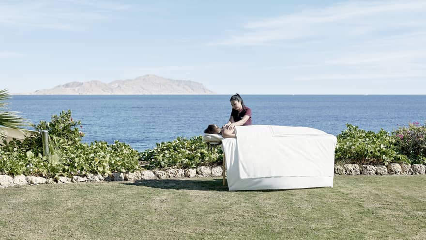 Massage therapist during an outdoor session with blue skies and views of the Red Sea