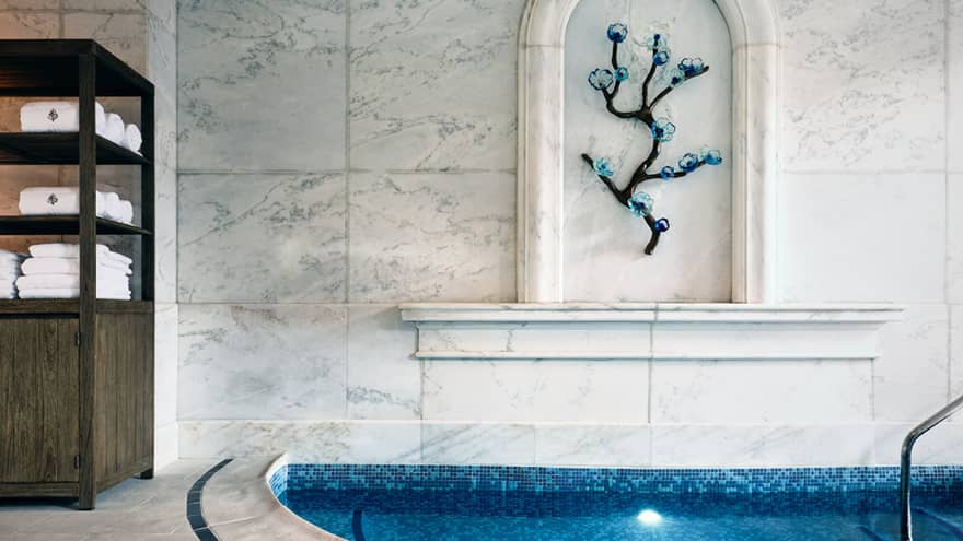 Spa tub with shelves of towels and artwork on the wall.