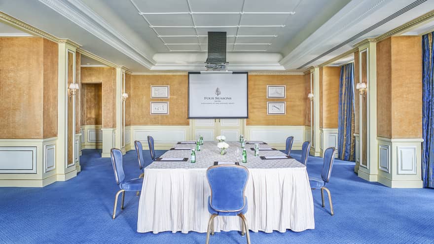 Empty boardroom with physically distanced place settings and hybrid setup with camera and screen