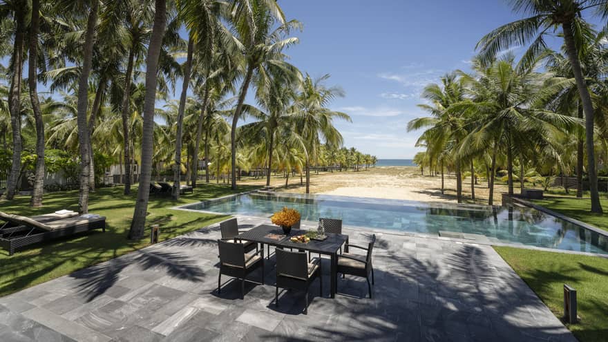 Three-Bedroom Pool Villa pool area with dining table, lounge chairs, palm trees, ocean views