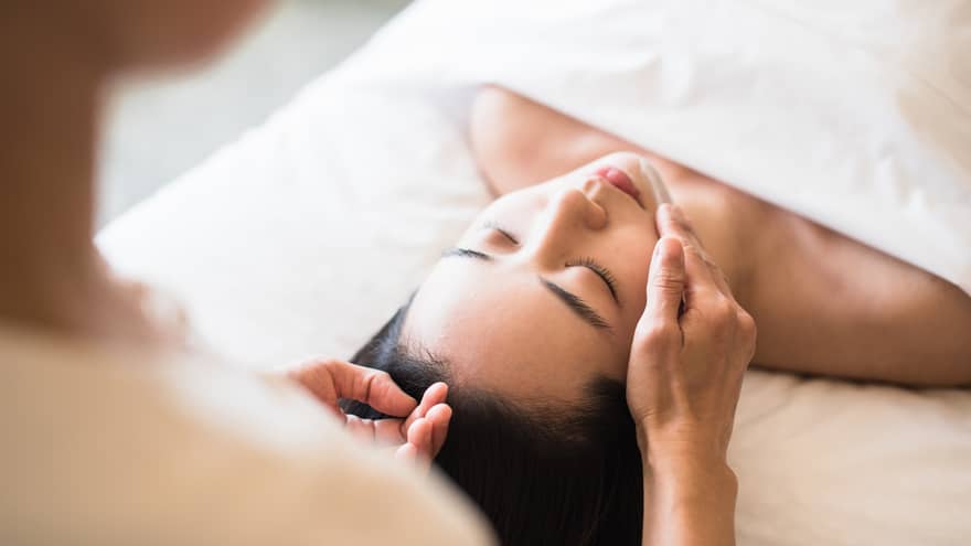 A guest receiving a soothing facial at a spa, lying on a massage table, surrounded by calming décor and soft lighting.