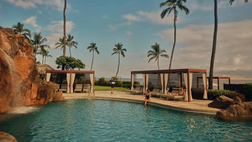 Waterfall swimming pool with cabanas and palm trees