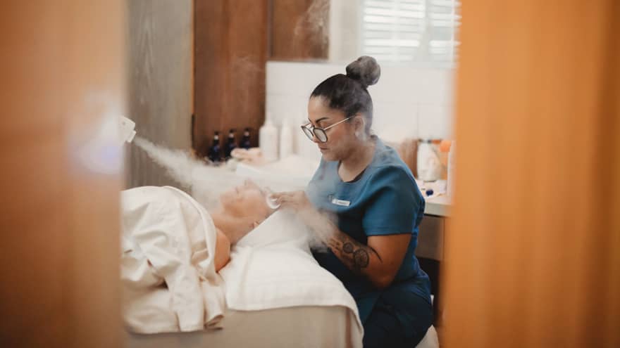 A spa team member giving a patron a facial with steam.