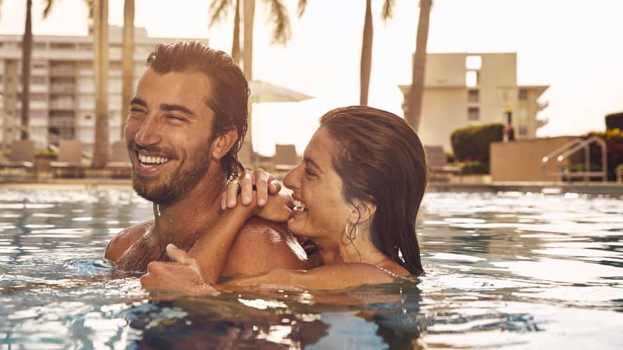 Man and woman laugh in pool