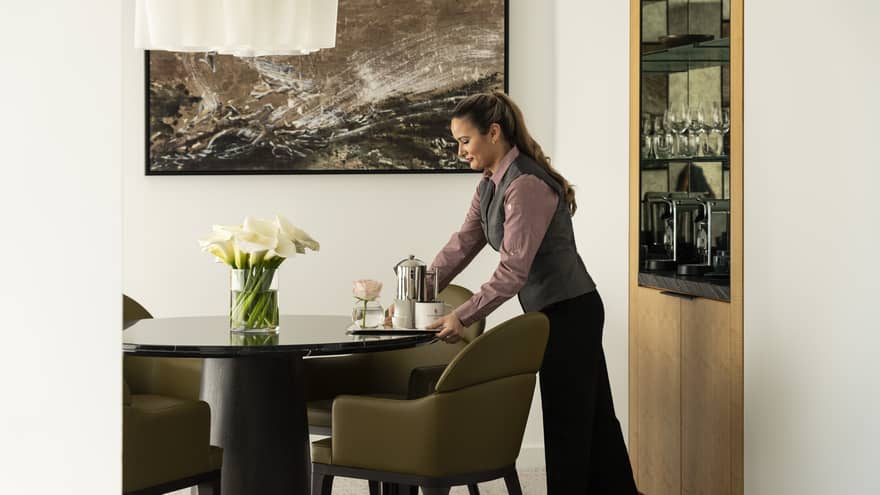An employee delivers a tray with coffee to a suite