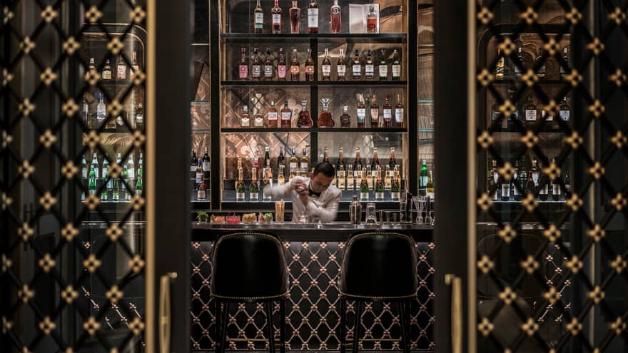 Bartender shakes drink behind dark Nautilus Bar with black-and-gold Art Deco-style design