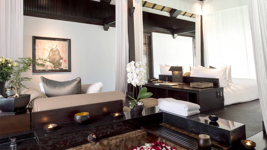 Pool Villa candle-lit tub filled with flower petals in middle of bright room, sofas
