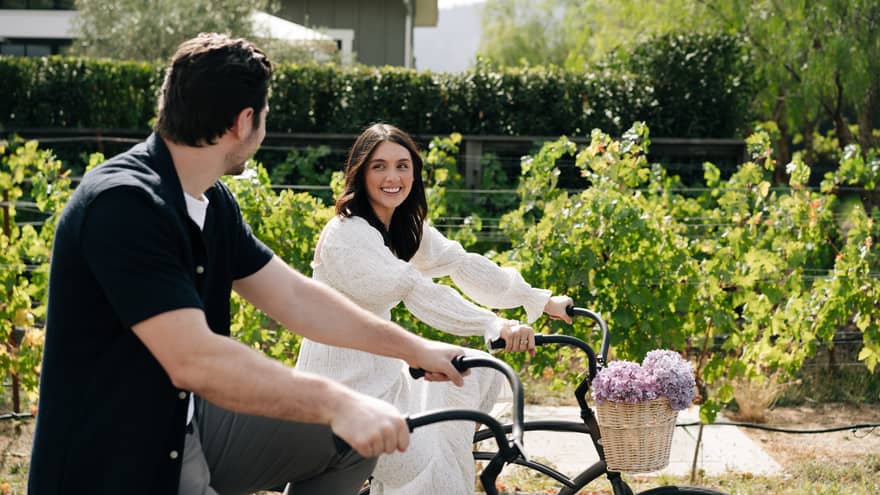 Man and woman riding bikes through the vineyard