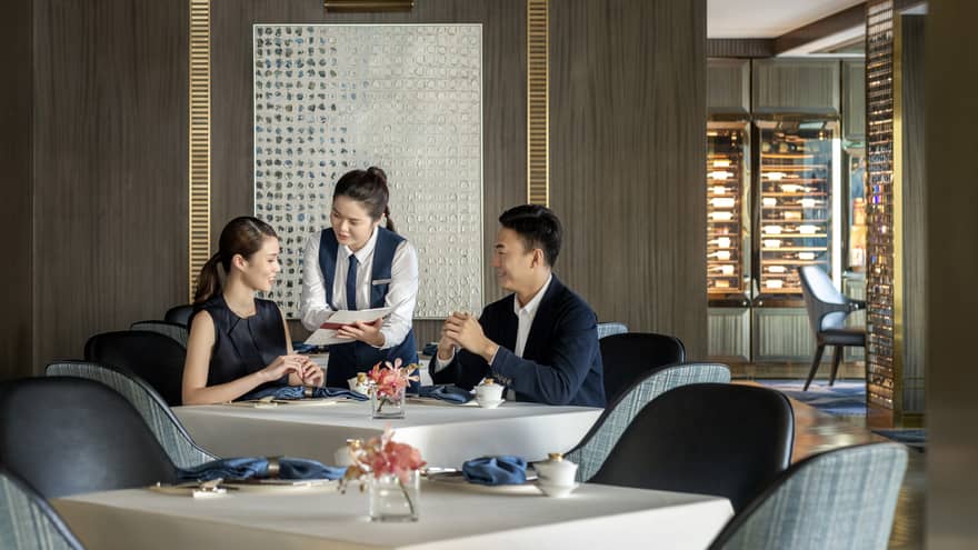 Waitress shows menu to couple dining at Vista 38