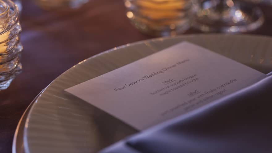 Close-up of wedding menu on dining plate near glowing candles