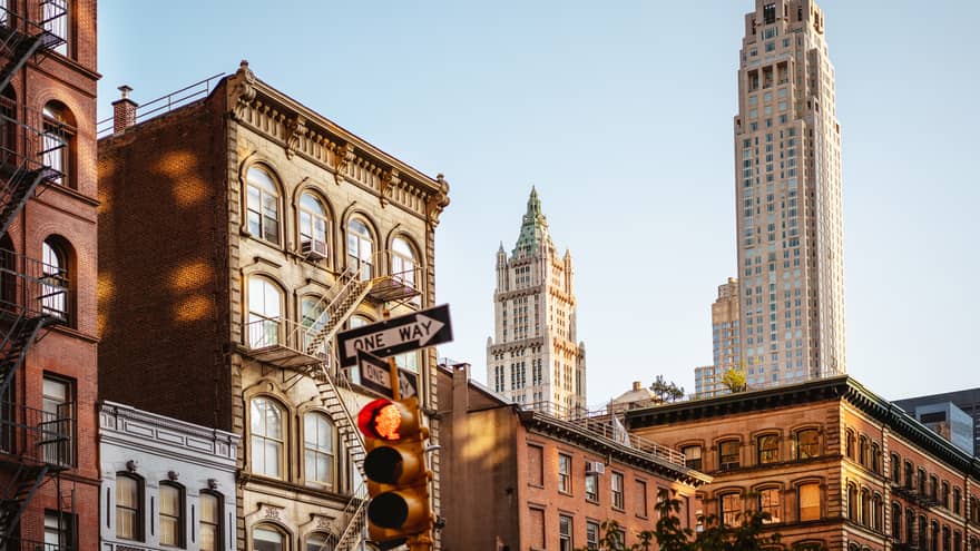 Daytime view of the top sections of classic New York buildings with a traffic light in the foreground