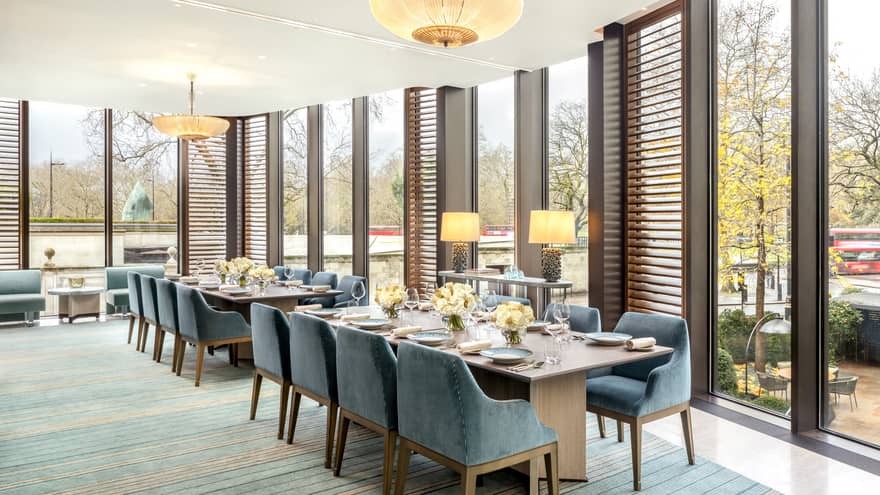 Two rectangular dining tables flanked with blue suede?covered chairs, set for a meal