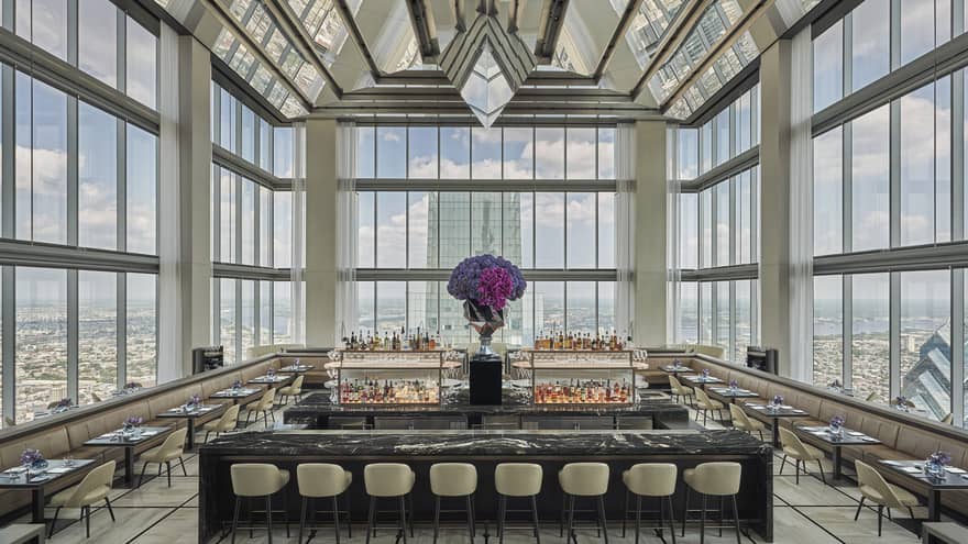 Glass penthouse bar and lounge with black and white marble bar, stools