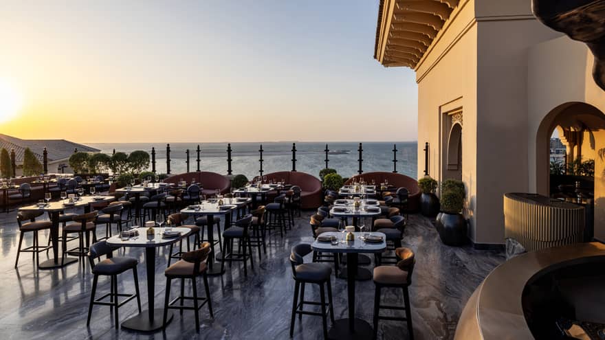 Rooftop bar of Dubai hotel during the day, with many tables and chairs and sea view