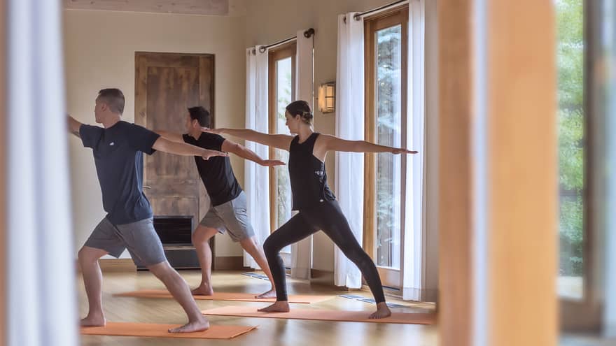 Three people perform yoga pose in Fitness Centre