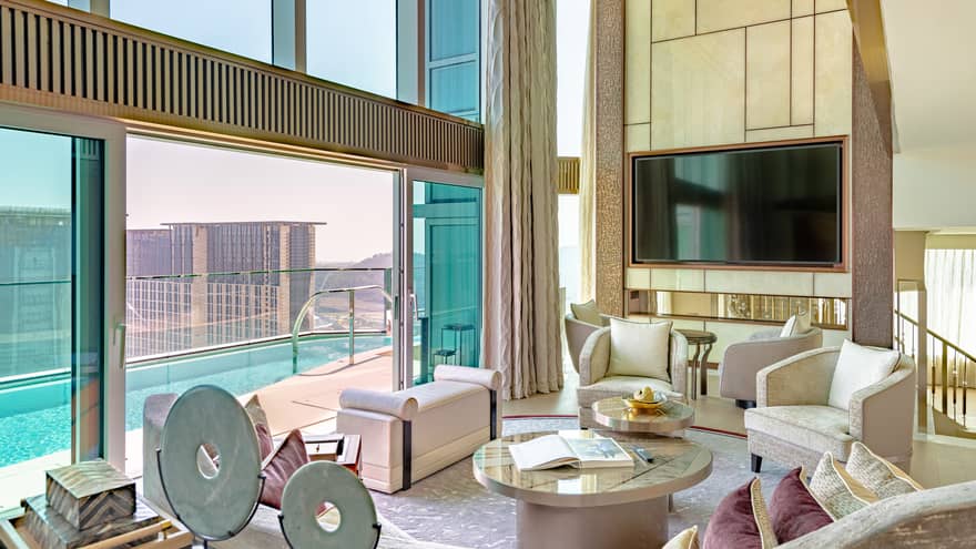 A spacious, stylish living room with sliding doors opening onto a private pool that overlooking a cityscape. 