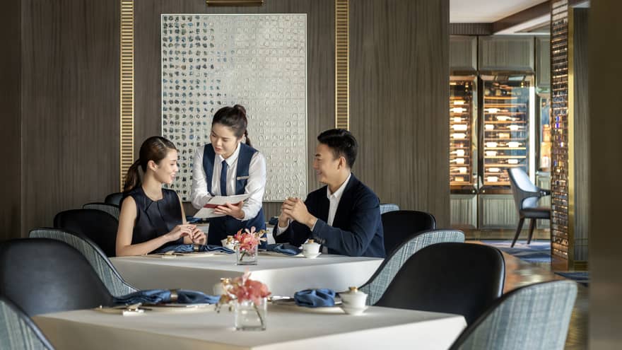 Waitress shows menu to couple dining at Vista 38