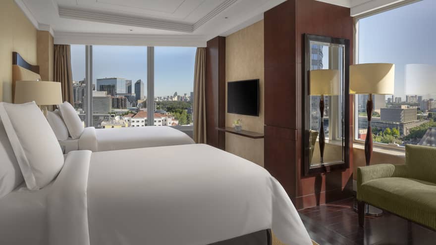 Hotel room with two single beds, windows on two walls, green love seat