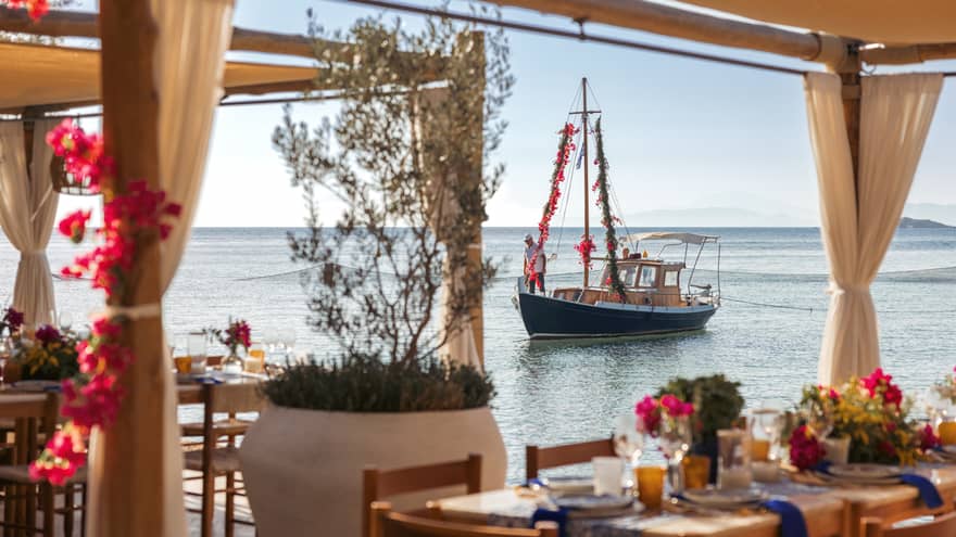 View of sailboat on calm Saronic Gulf through waterfront restaurant patio of Taverna 37