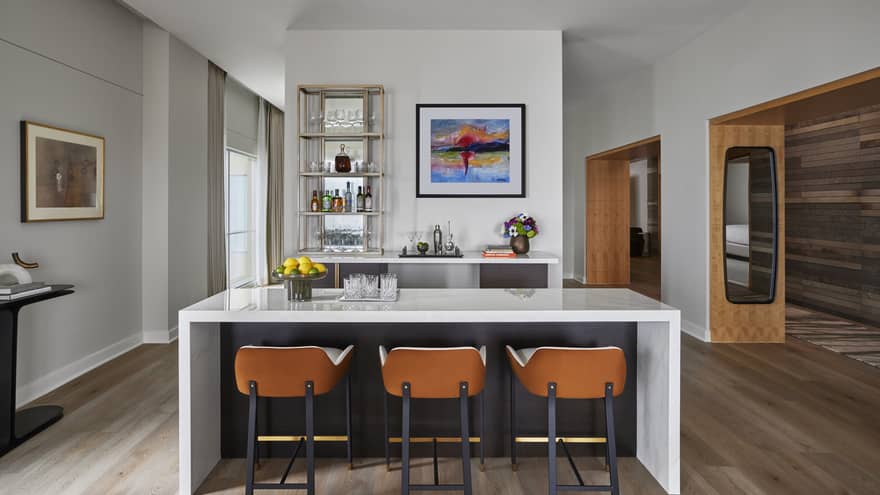 Bar area with marble island, three modern bar chairs and glass shelves