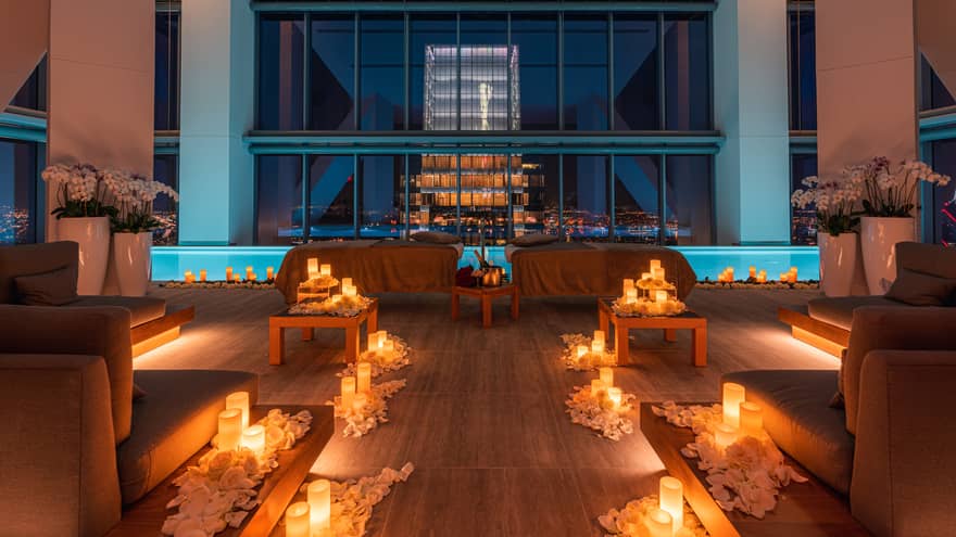 Couples massage beds under window in candle-filled room at night