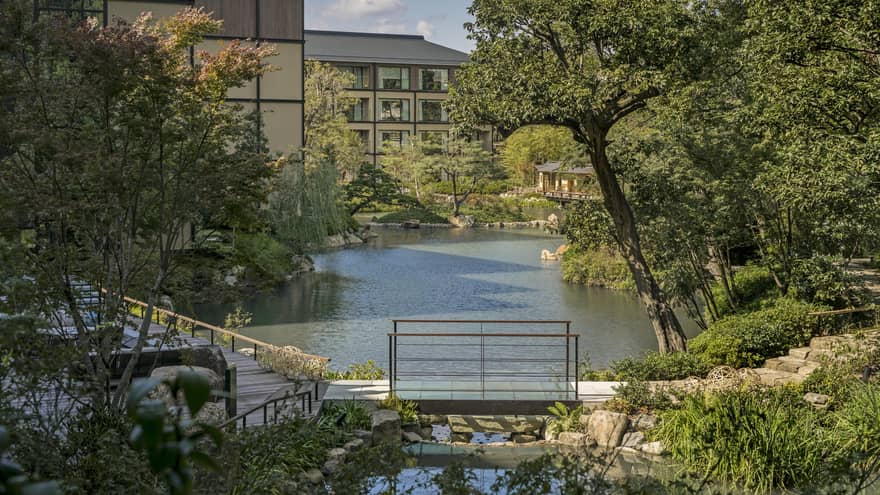 Trees, Shakusuien garden around pond under Four Seasons Hotel Kyoto building
