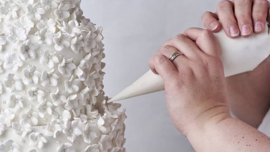 A person putting icing on a tall cake.