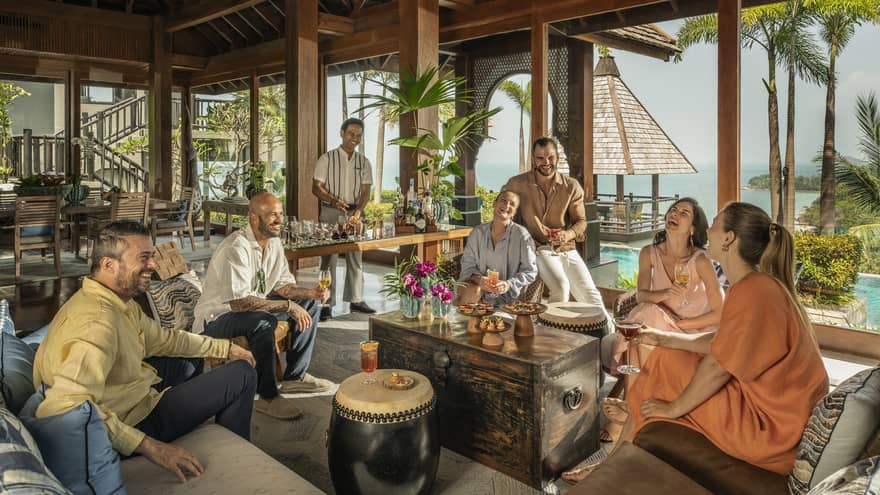 Laughing group of friends enjoy drinks made by their private bartender