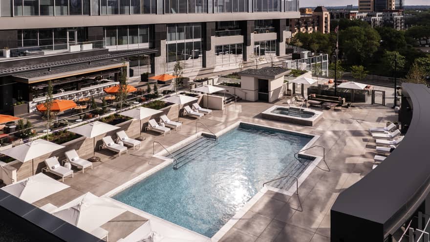 An outdoor pool surrounded by lounge chairs and large umbrellas.