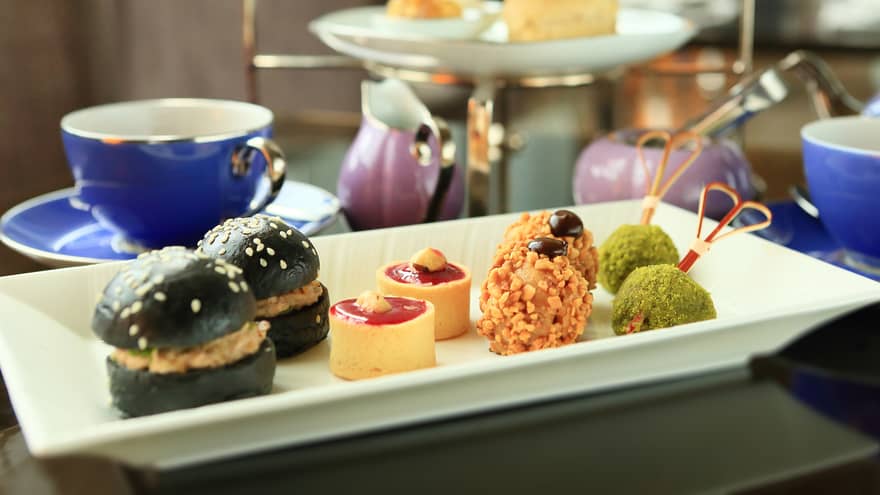 Small appetizers, sweets on white tray near tea service 