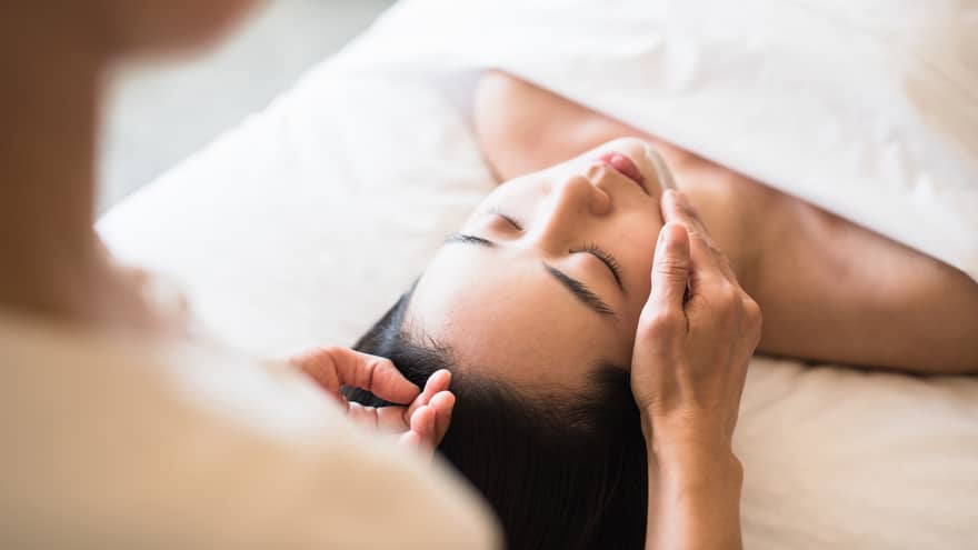 A guest receiving a soothing facial at a spa, lying on a massage table, surrounded by calming décor and soft lighting.