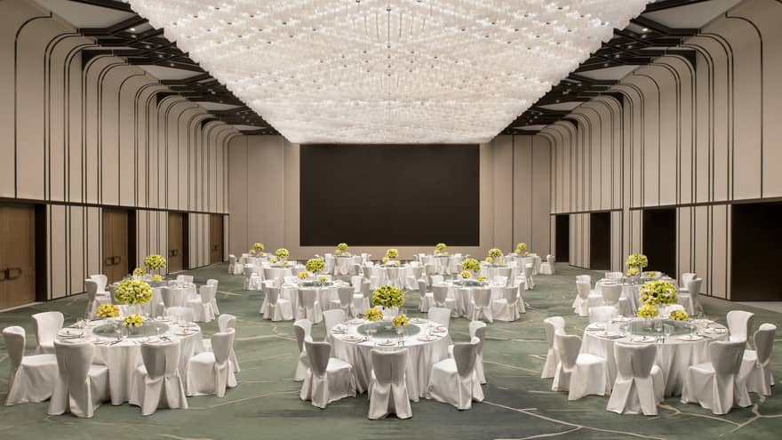Grand ballroom with a ceiling-sized lighting display, white tables and chairs set up for a banquet event