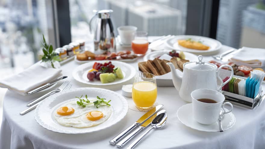 Luxurious in-room breakfast at Four Seasons Hotel Osaka with city views, eggs, fruit, and coffee.