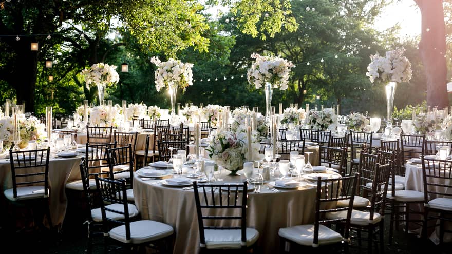 White floral arrangements on round banquet tables at outdoor wedding