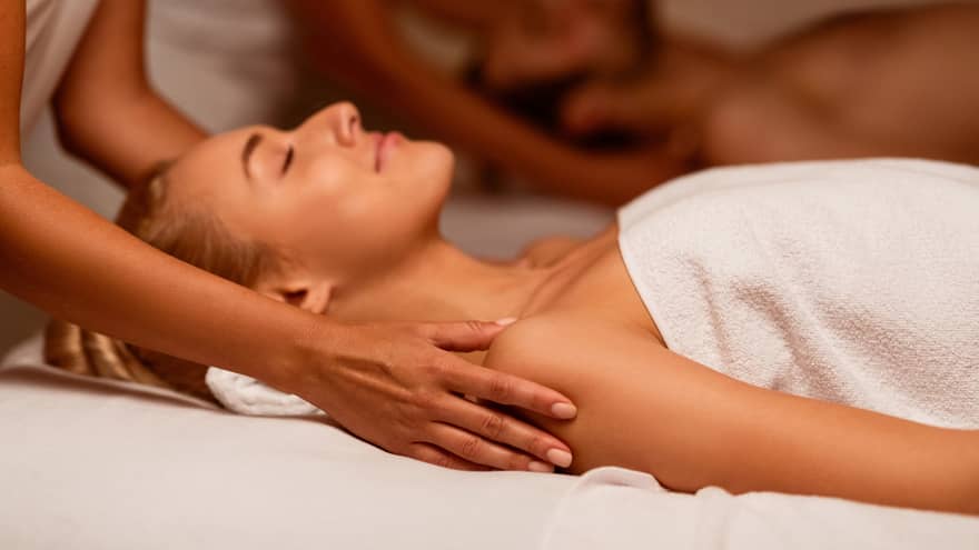 Two spa therapists perform a couples' massage