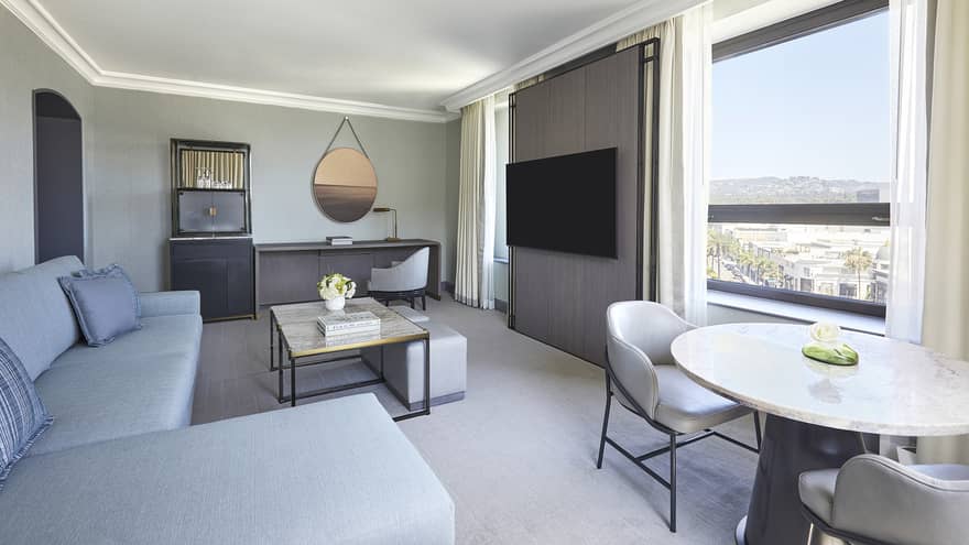 Living room with light blue sofa, table and two chairs, desk and wall-mounted TV