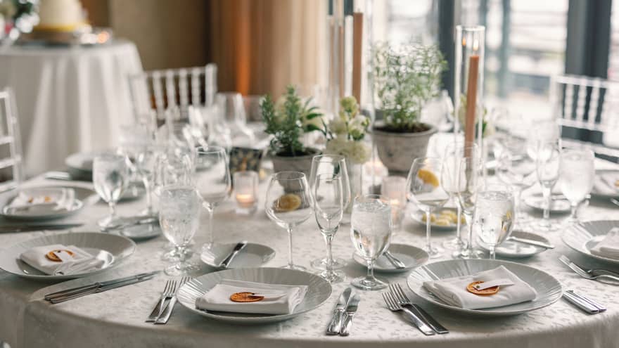 A dining table set with plates, utensils, napkins, wine glasses and candles