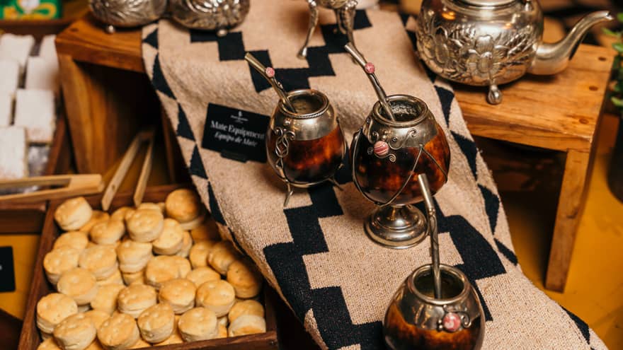 Traditional Argentine mate cups sit next to silver tea pots and a display of pastries