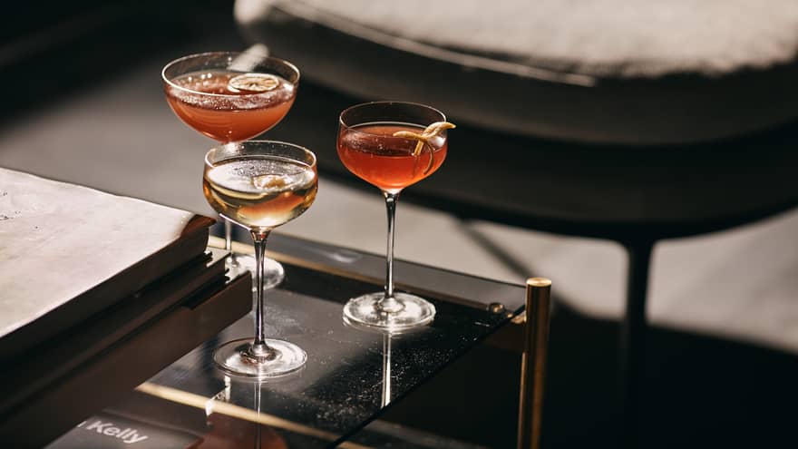 Three wine glasses with orange slices on a table.