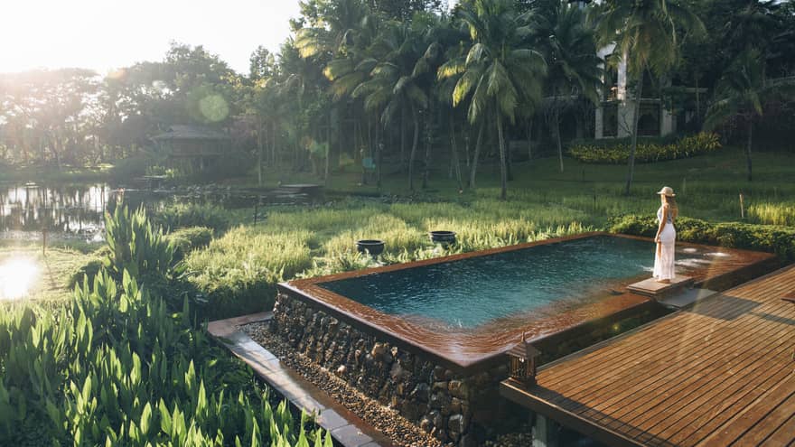 Woman stands at edge of infinity pool overlooking the rice paddies