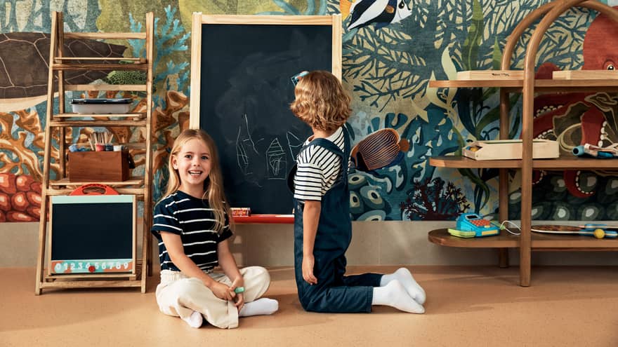Two children play in play area with chalkboard