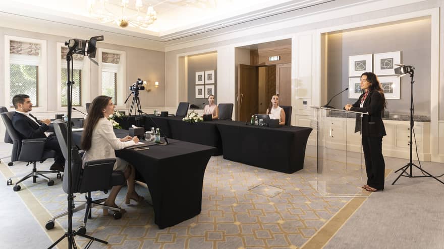 Hybrid meeting boardroom setup with audiovisual equipment and speaker at dais