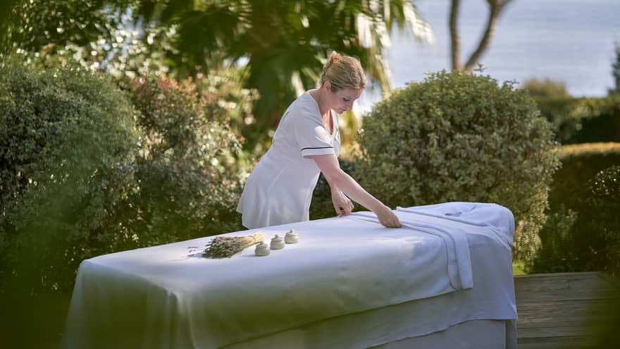 Spa therapist preparing spa bed on terrace overlooking Mediterranean