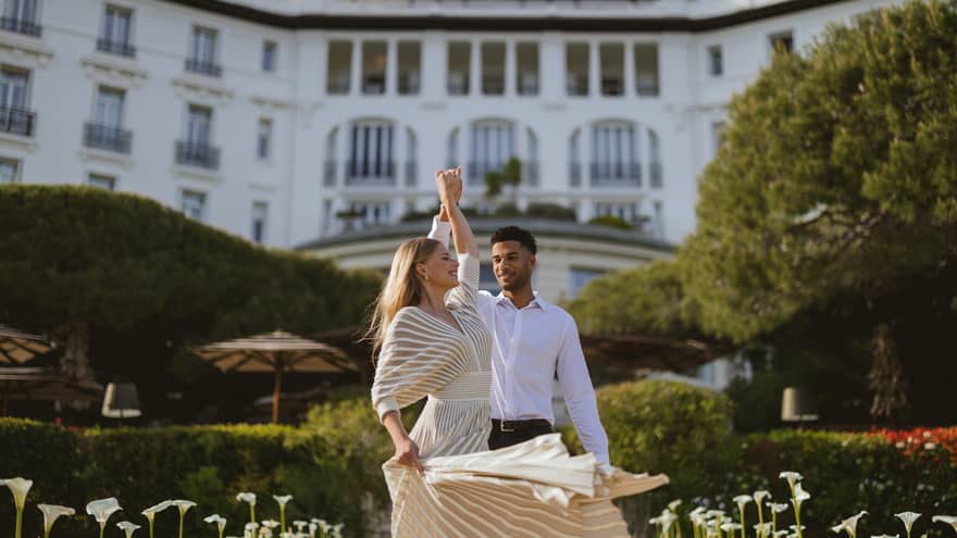 Couple dancing in front of large stately white building with gardens